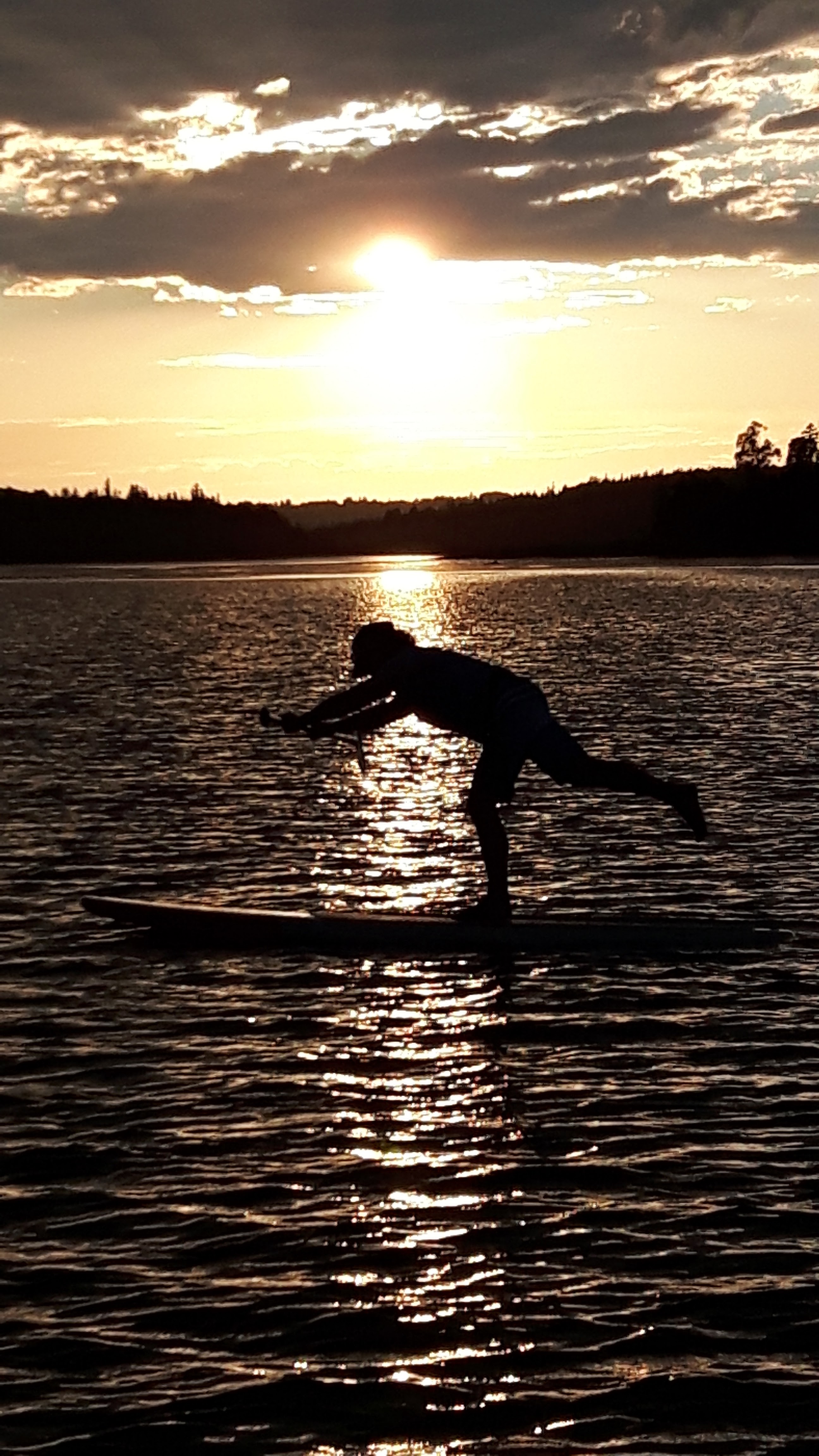 Person in silhouette doing yoga on a paddleboard at sunset, representing flexible rentals